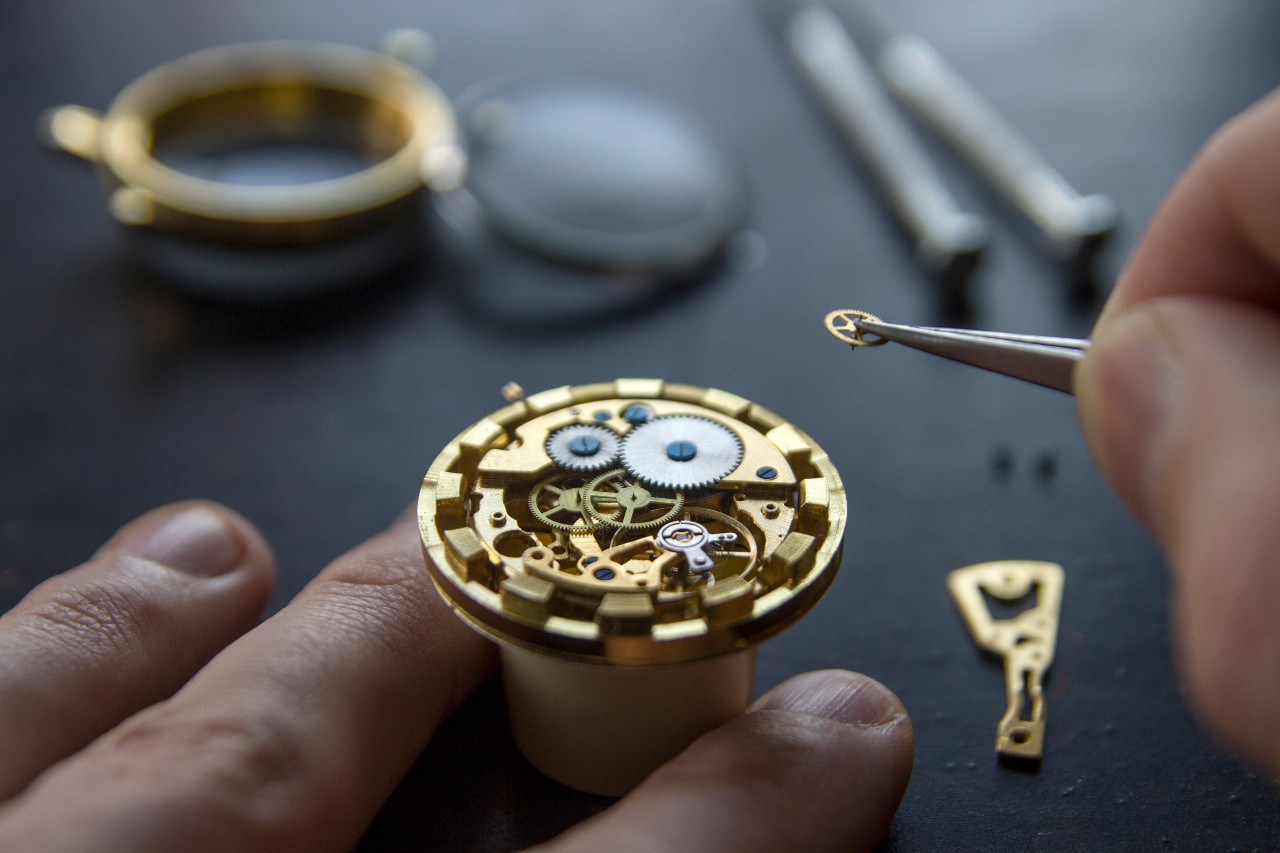 An expert replaces a gear in the movement of a mechanical watch.