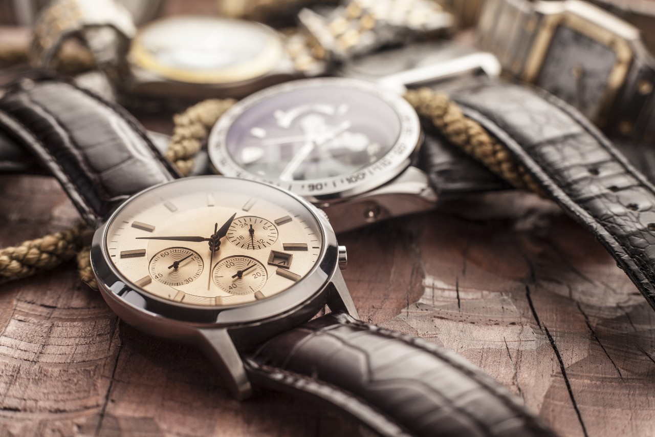 A group of watches lay on a wooden surface with boating rope.