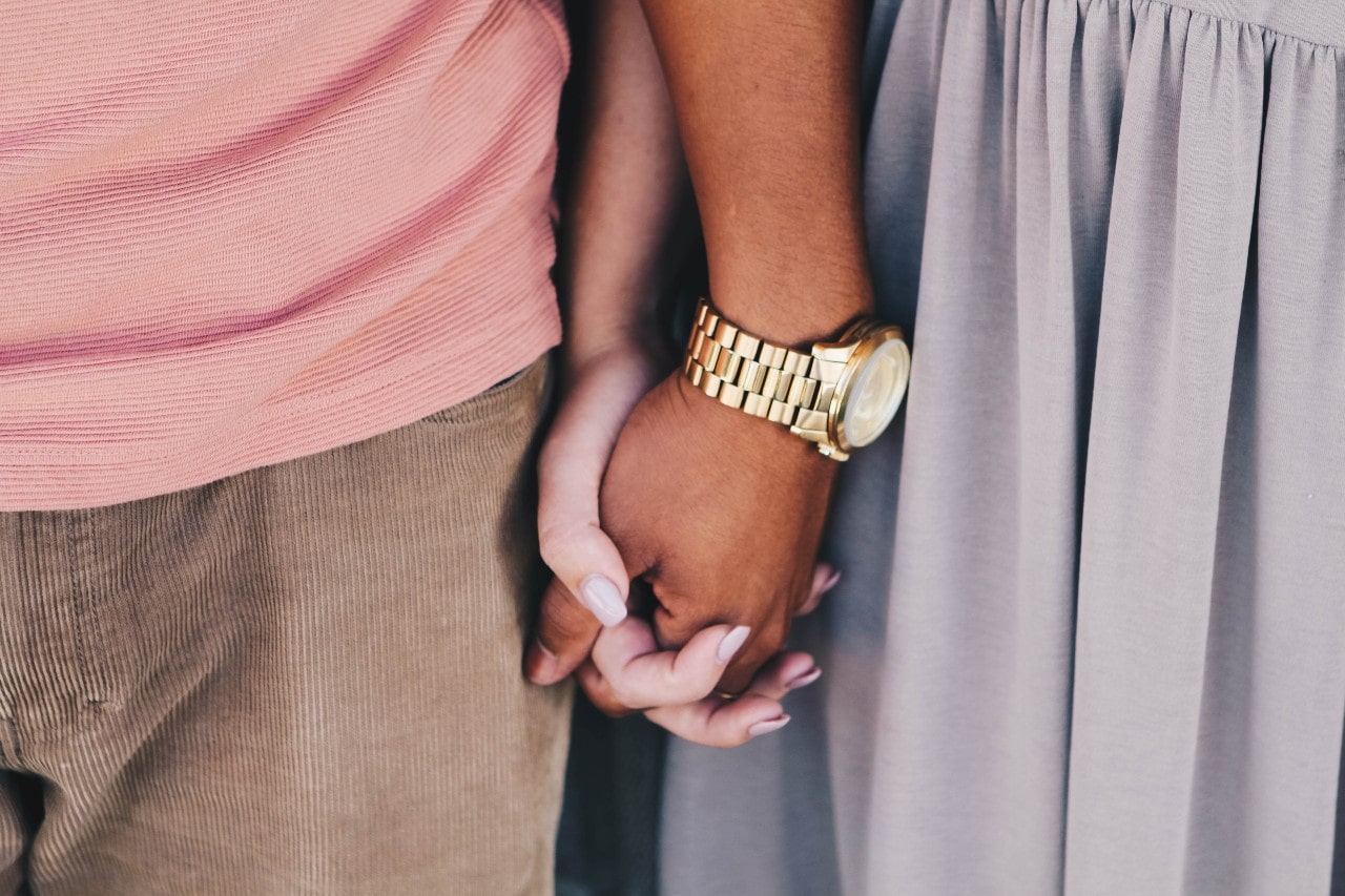a couple holding hands, the man wearing a large gold watch