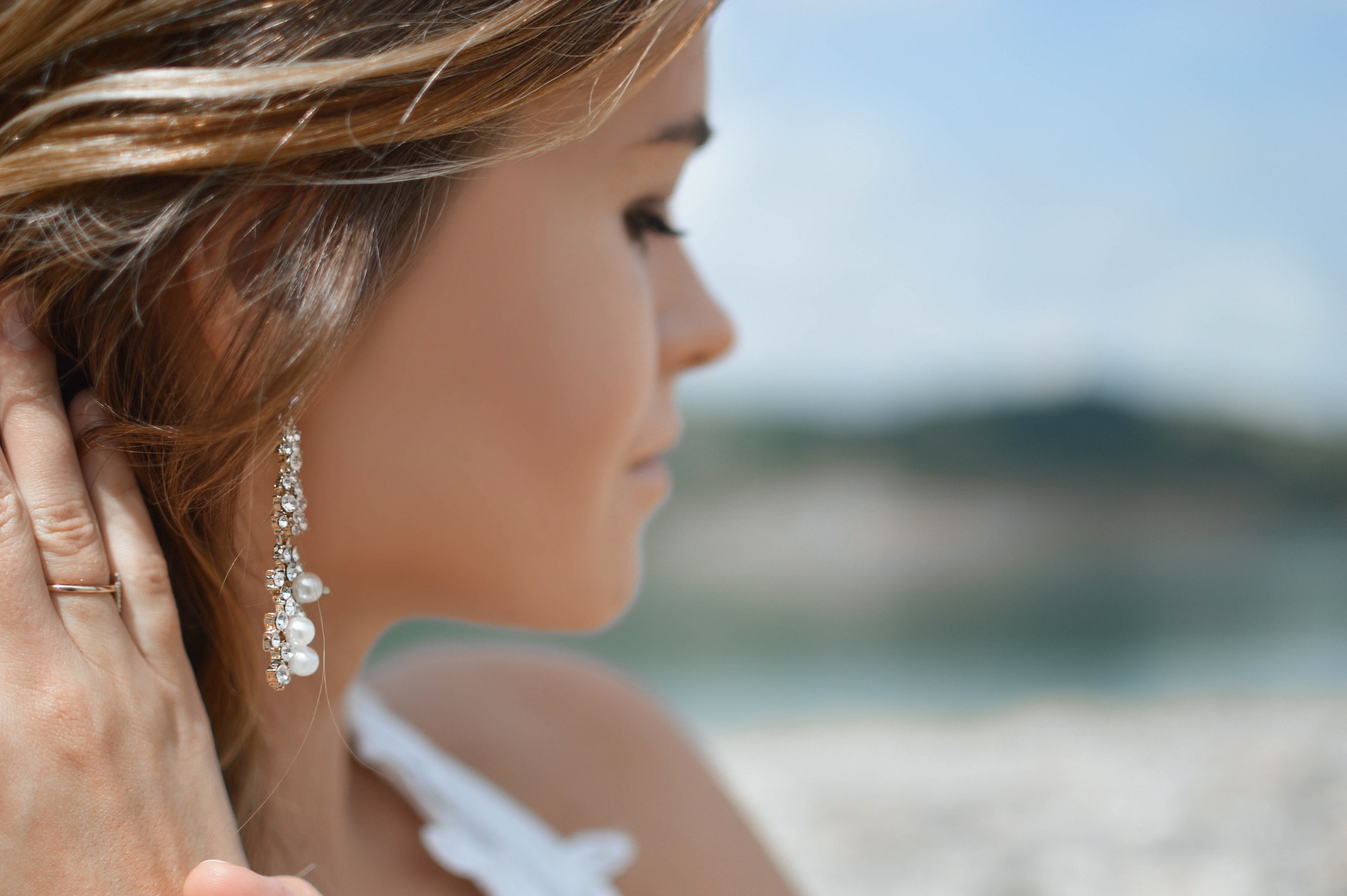 a woman looking away from the camera wearing long pearl and diamond earrings