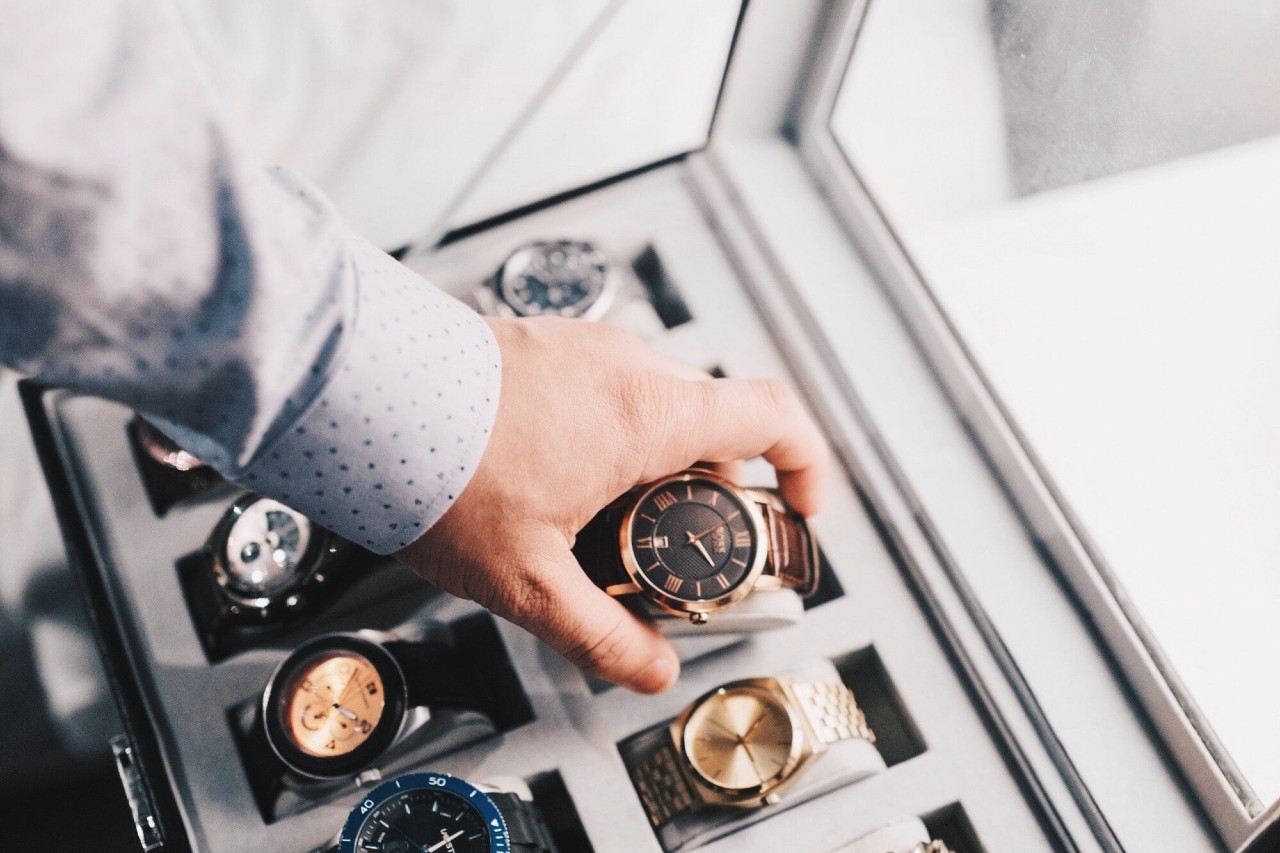 A well-dressed man selecting a luxury watch from a display case.