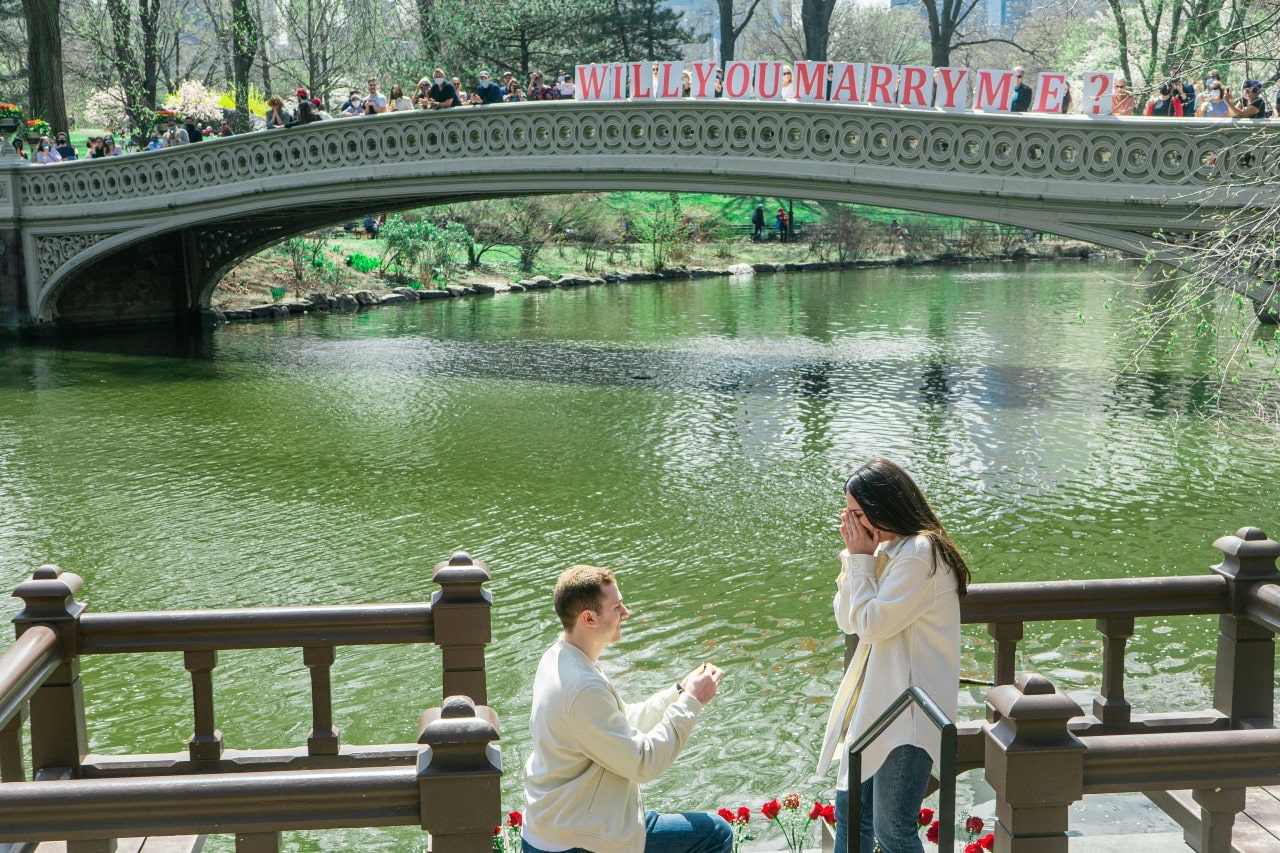 a man kneeling and proposing to a woman at Central Park in New York