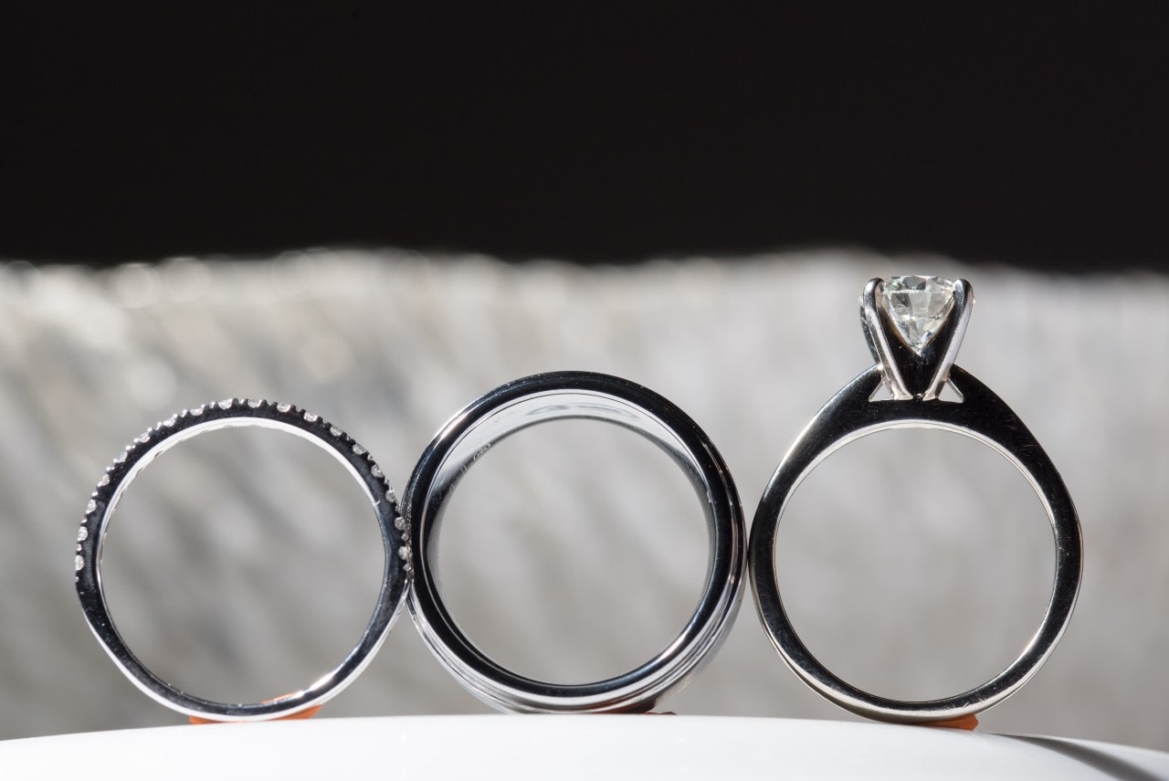 Three distinct white gold engagement rings displayed side-by-side, the rightmost one with prominent shoulders.