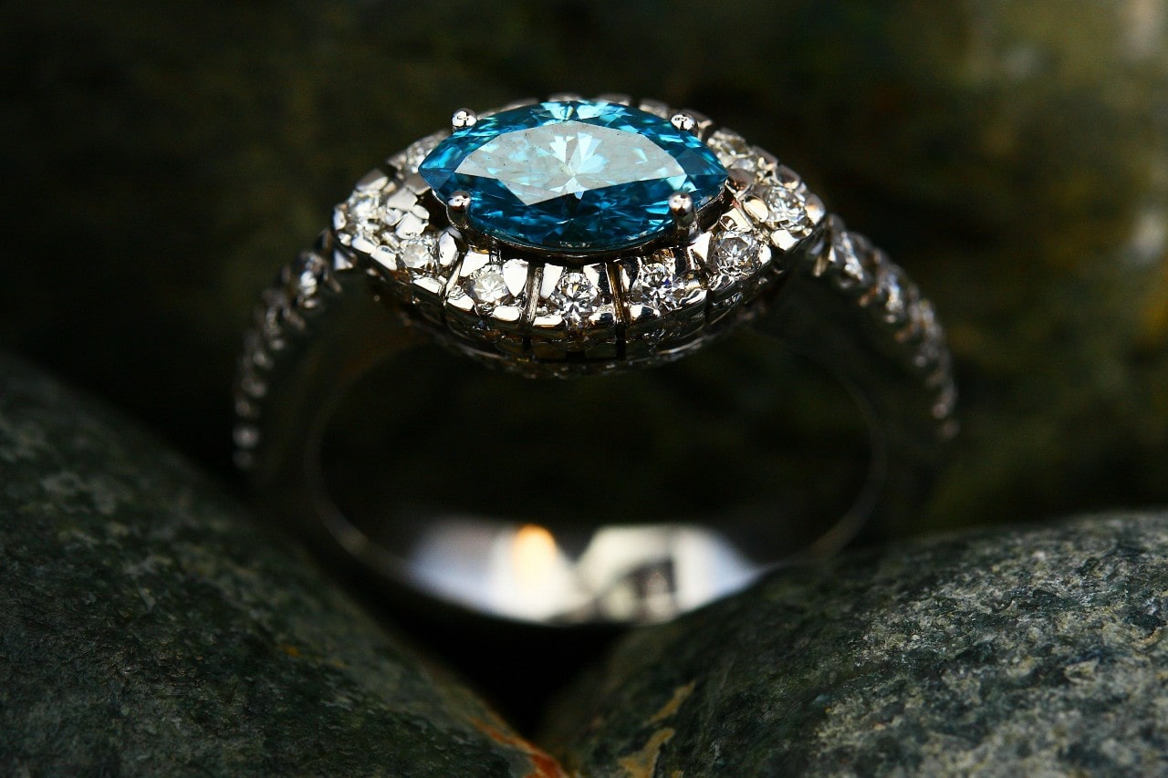 close up image of an engagement ring with a blue center stone with an east west orientation