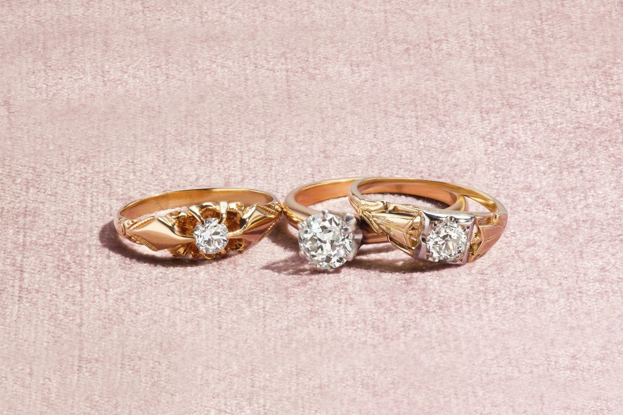 three yellow gold engagement rings with wide bands and unique details