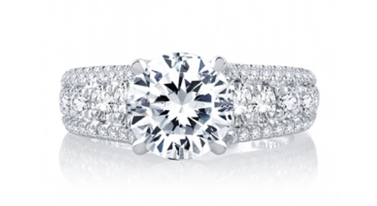 an engagement ring with a round cut center stone and a wide band