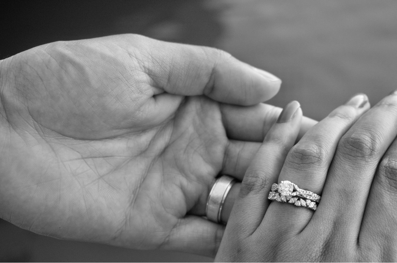 a couple holding hands in black and white – the woman’s hand adorned with a round cut engagement ring