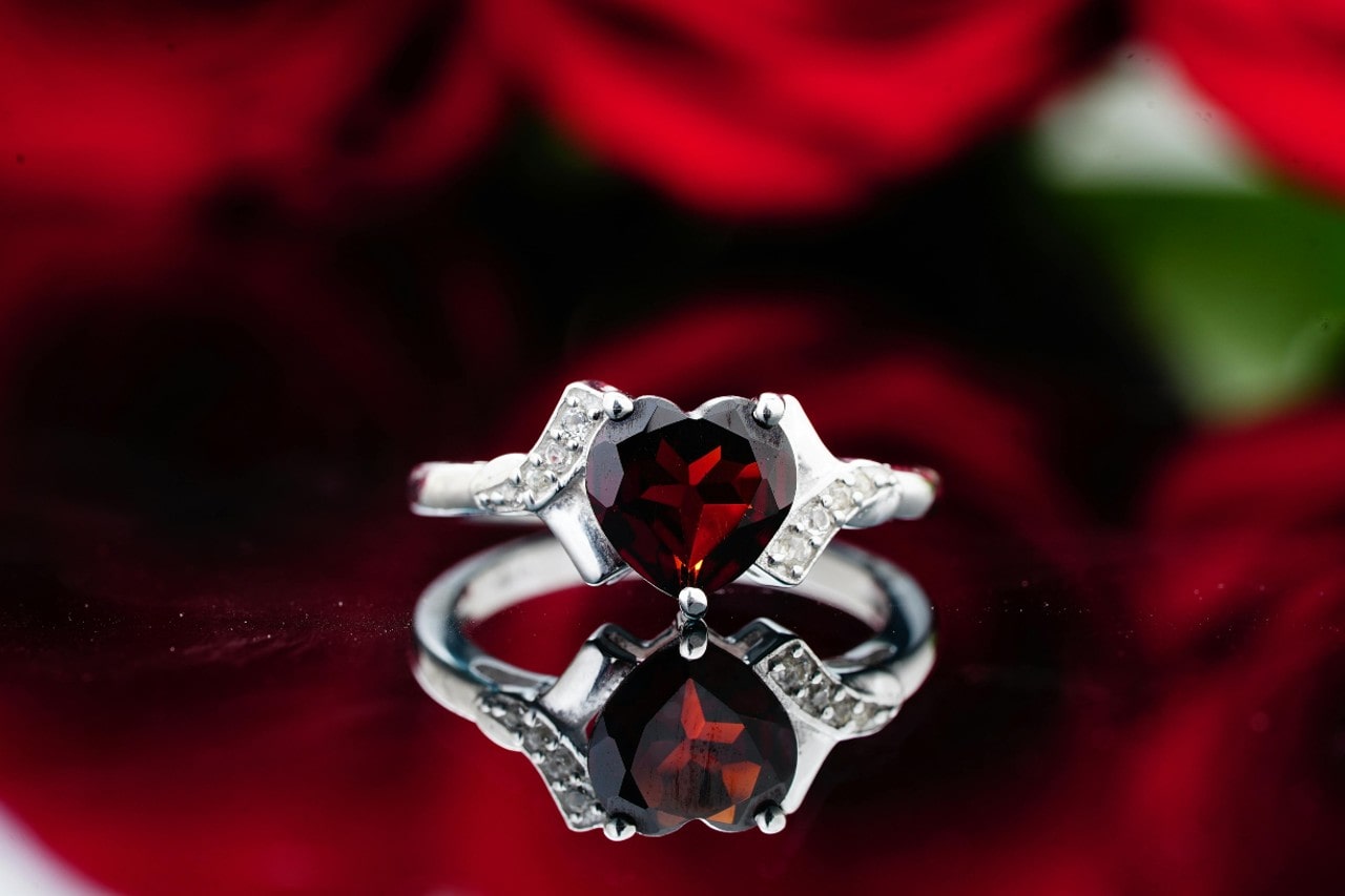 heart shaped ruby engagement ring with rose background