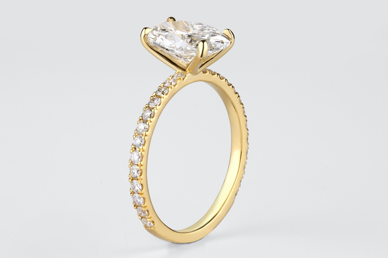 A yellow gold side stone engagement ring with one oval cut center stone.