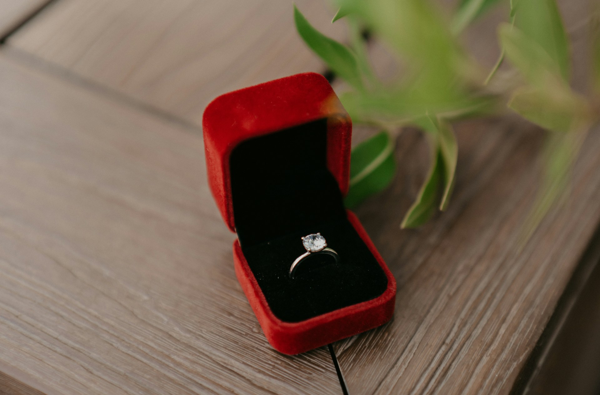 a dainty white gold solitaire engagement ring in a red ring box