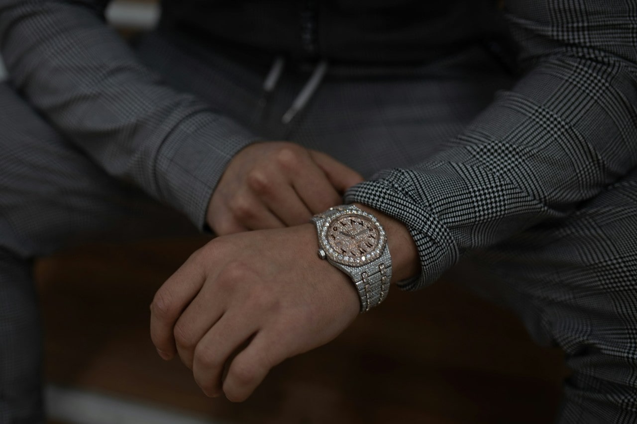 a person in a gray suit wearing a diamond studded watch