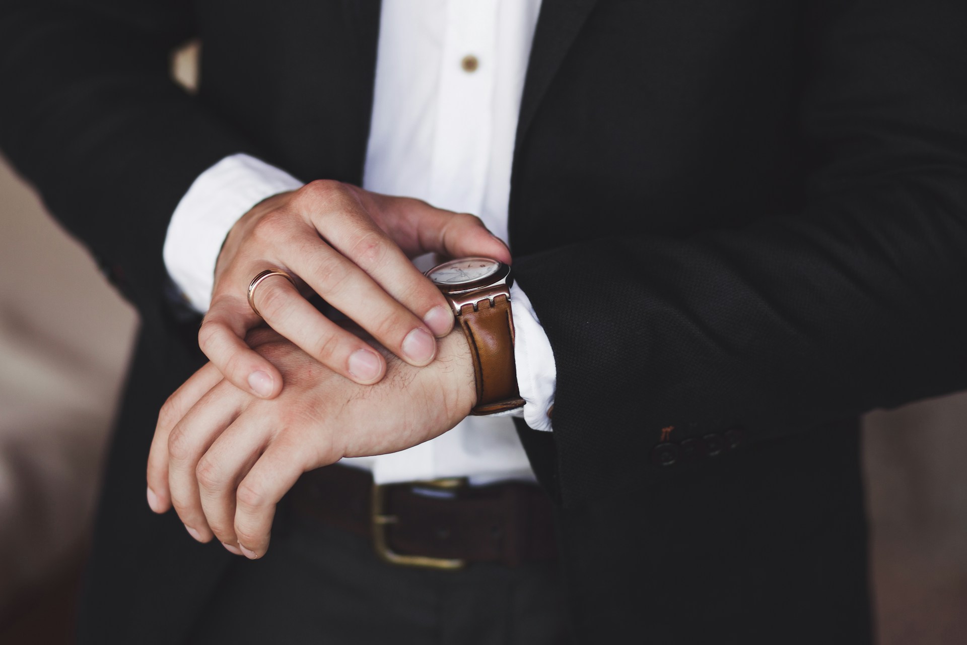 A close-up of a well-dressed man checking his luxury watch.