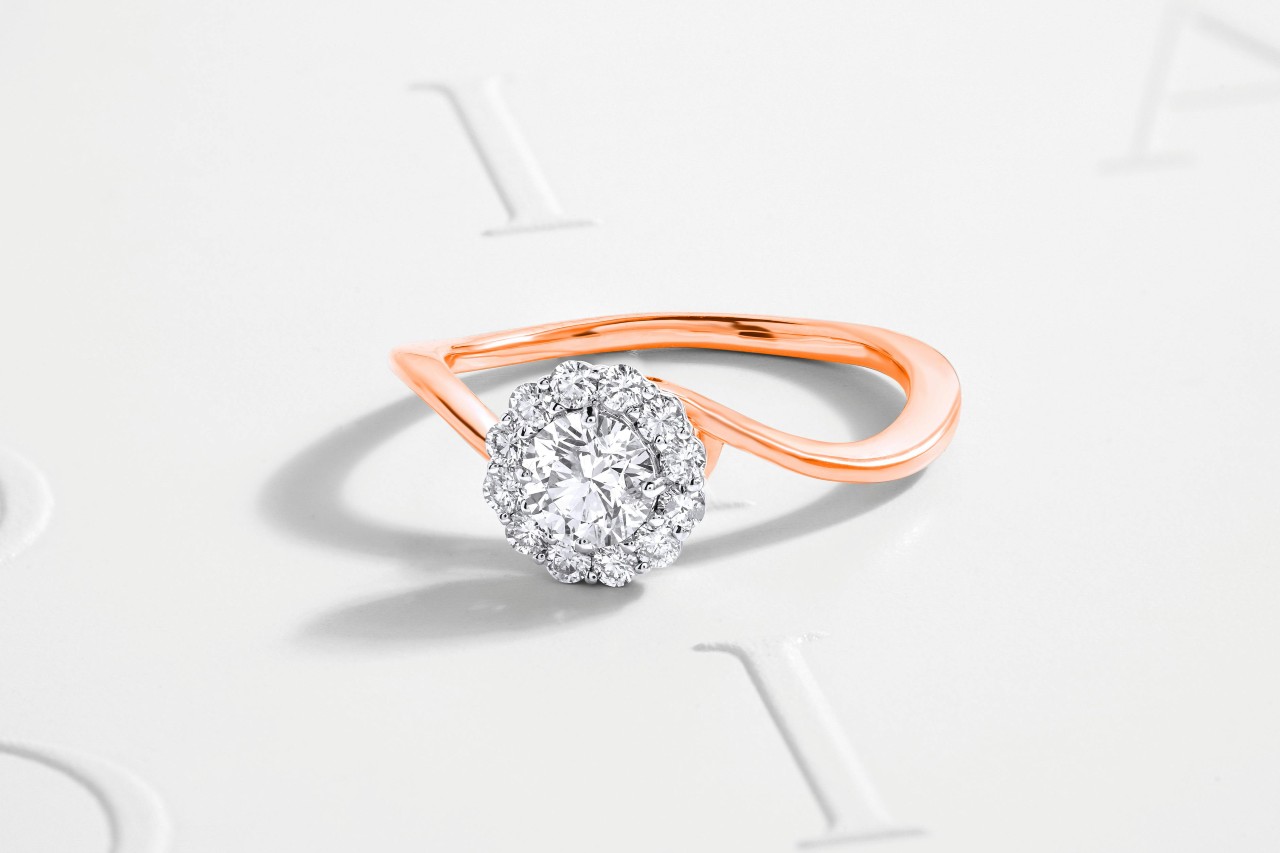 A mixed metal engagement ring with a rose gold curved band and a halo setting.